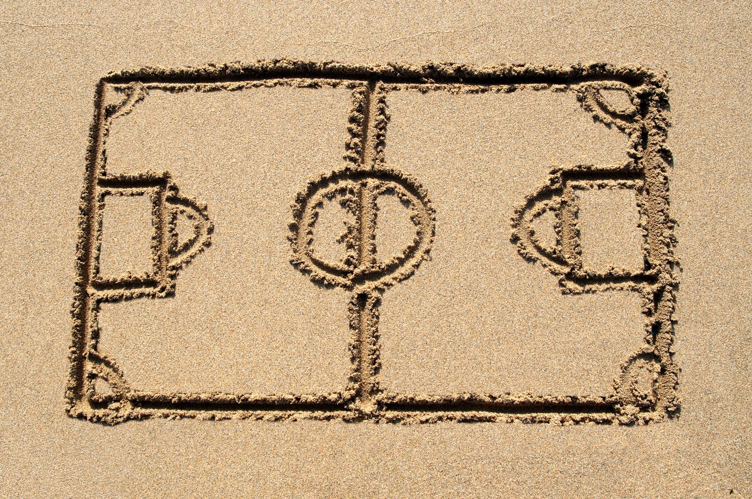 A soccer pitch drawn on a sandy beach.